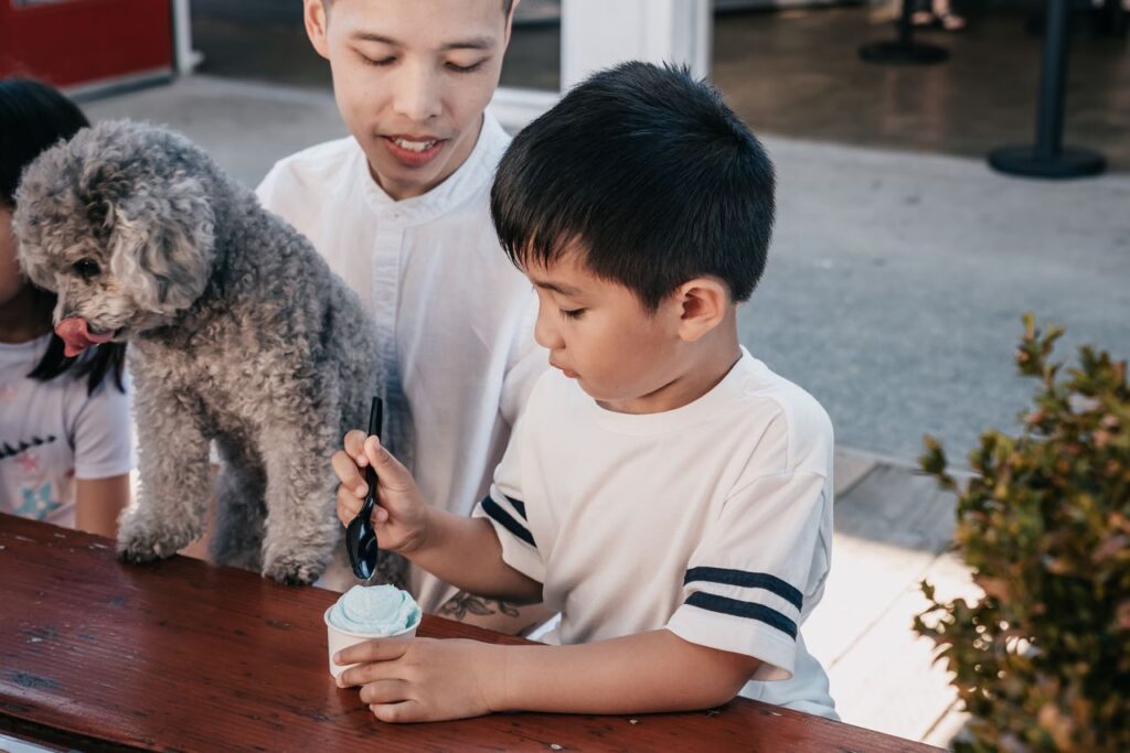 Mastering the First Impression: Your intriguing post title goes here A father and son bonding over ice cream with their pet dog at an outdoor setting.